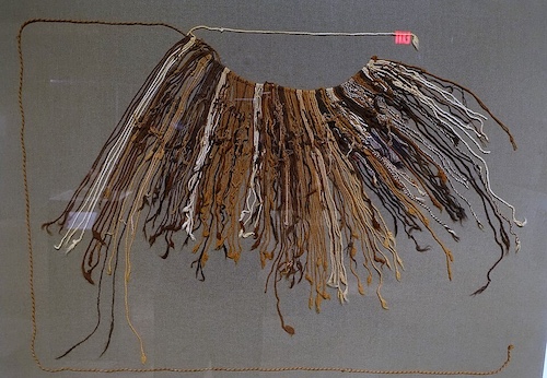 The quipu is a long horizontal string of knotted cords in various earth colors from white to brown to black, and not obviously of particular lengths.
Photo by Daderot. Exhibit in the Dallas Museum of Art, Dallas, Texas, 2017. Public domain via Wikimedia Commons.